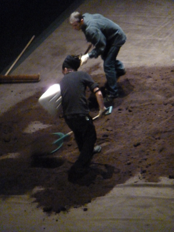 Deux hommes pelletant de la terre sur scène