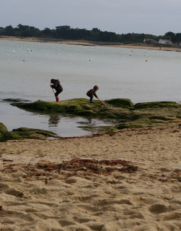 2 enfants jouant sur des rochers, bord de mer