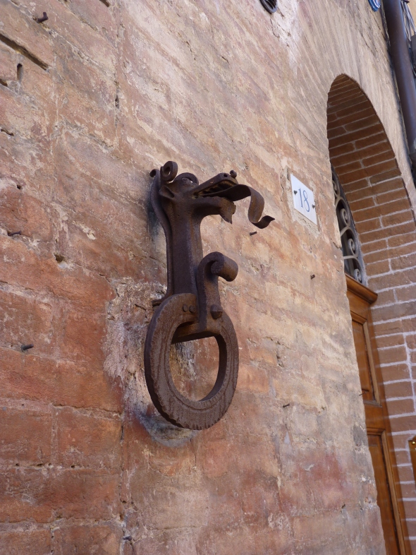anneau de fer surmonté d'une tête de dragon scellé dans le mur ocre